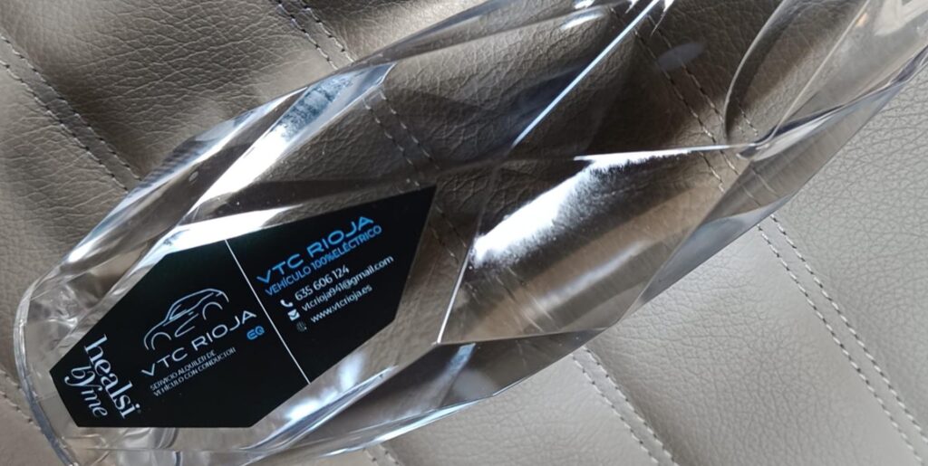 Botella de agua negra personalizada de VTC Rioja sobre un fondo plateado elegante.
